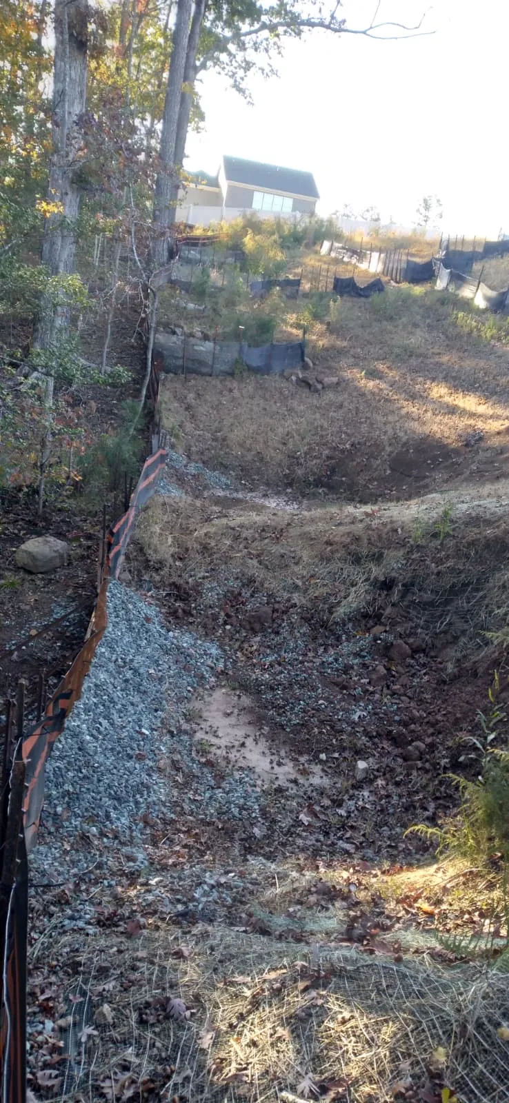 Rip-rap channel under construction on a fenced slope at Autumnwood