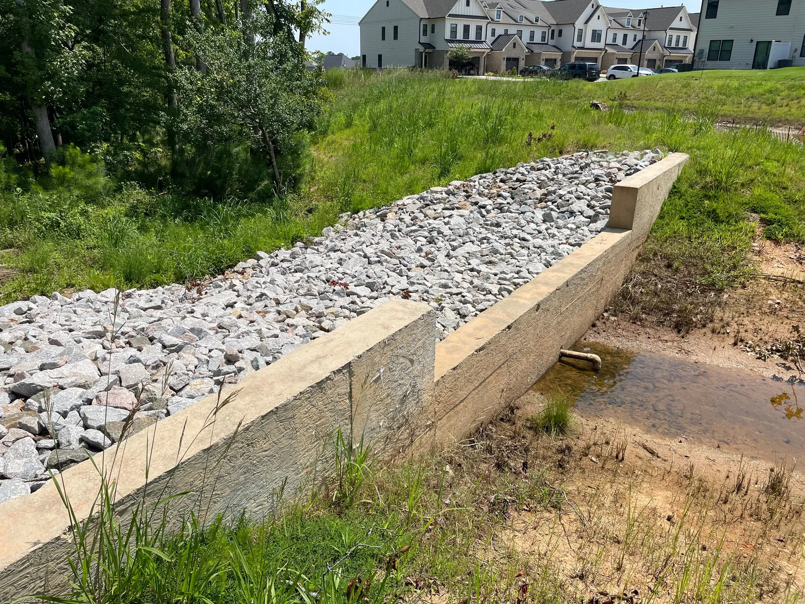 Concrete weir spillway with rip-rap channel near a townhome community