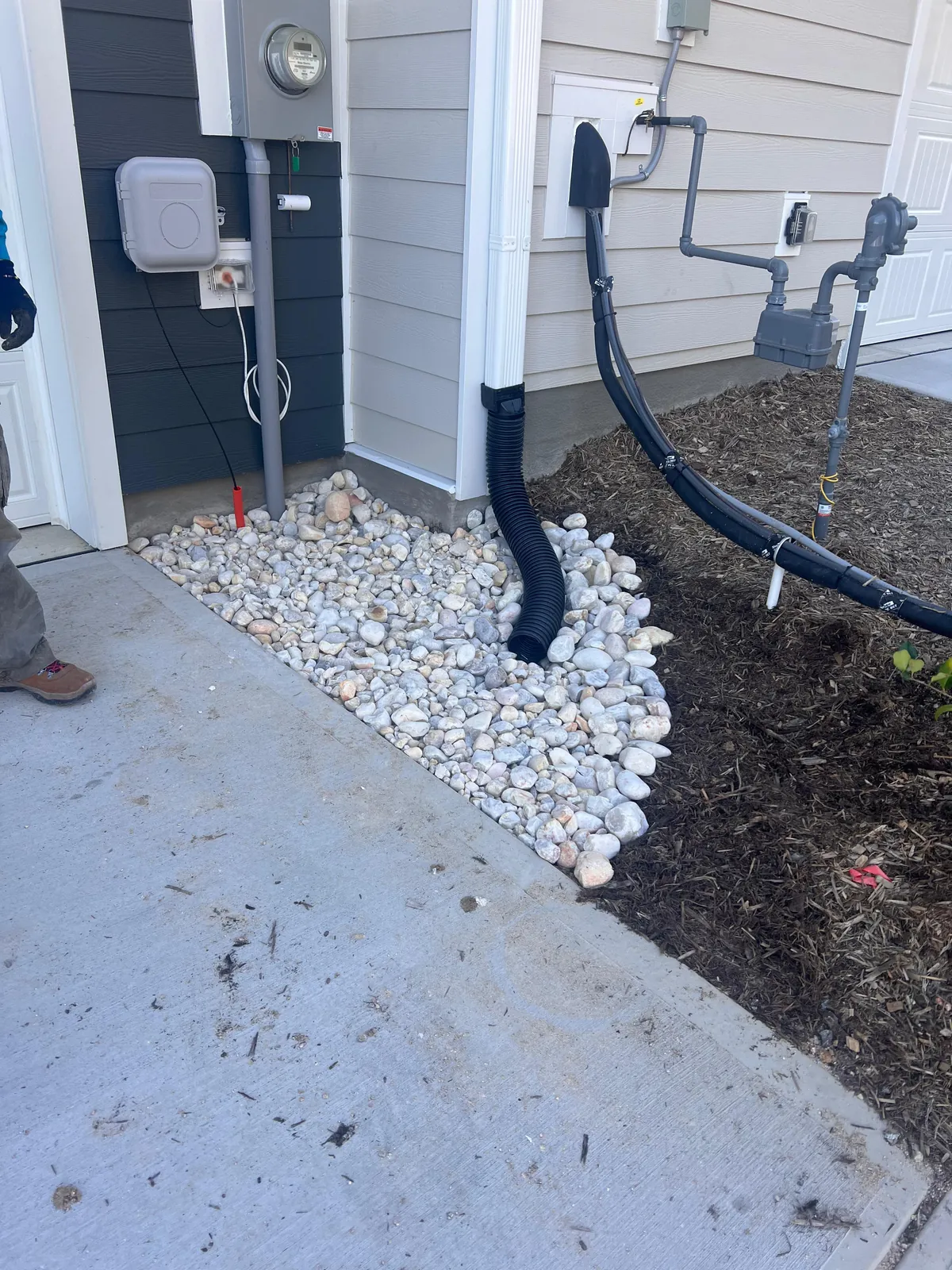 Downspout drainage rock bed at a townhome foundation