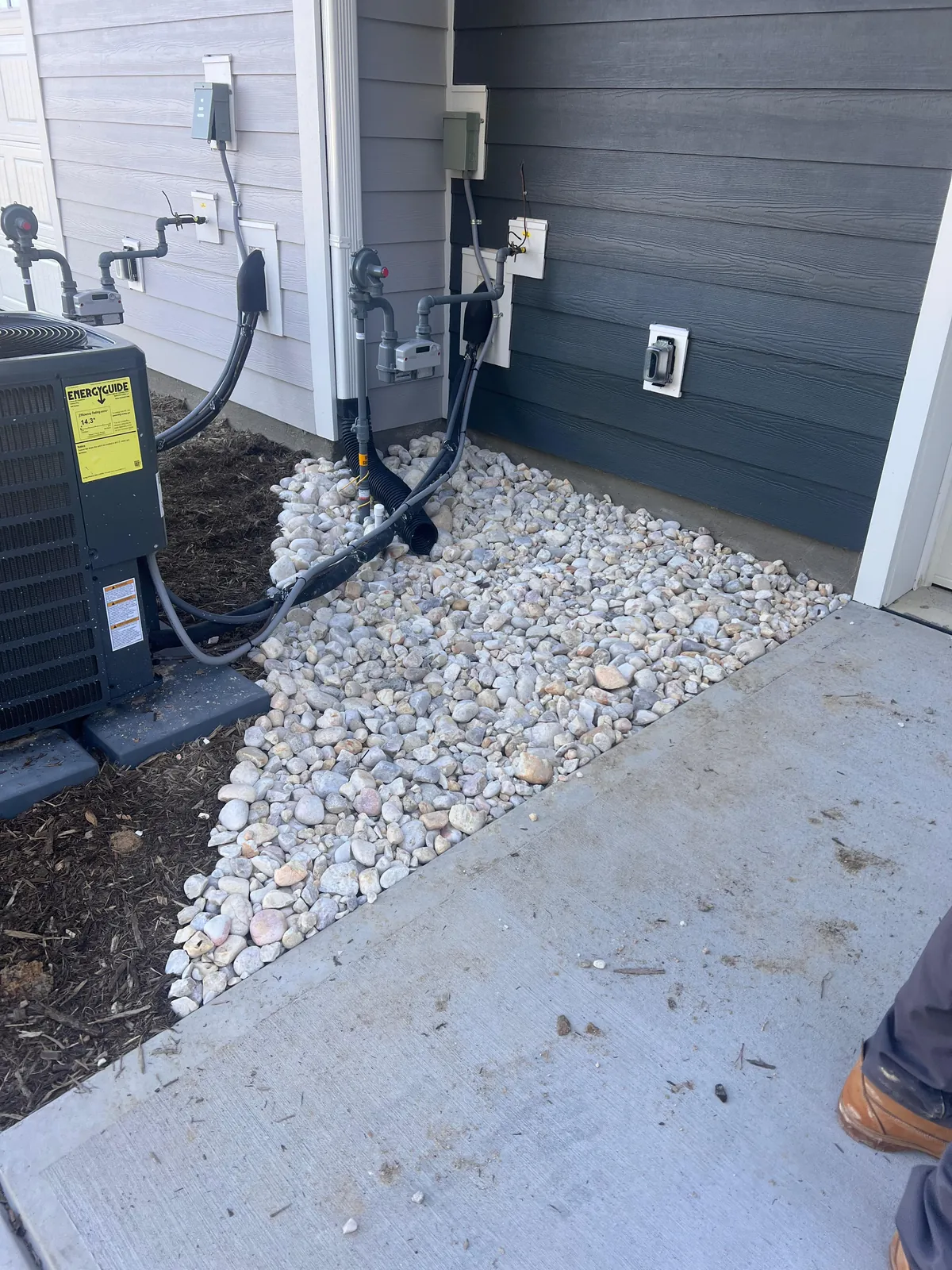 Downspout and equipment drainage rock bed at a townhome foundation