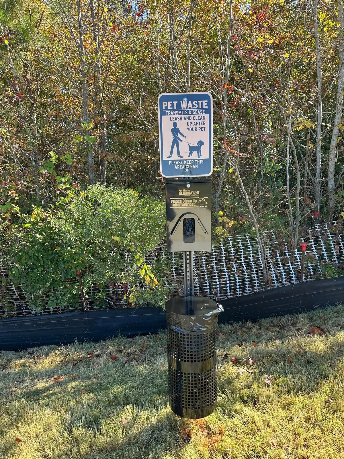 Pet waste station with signage and bag dispenser at a community