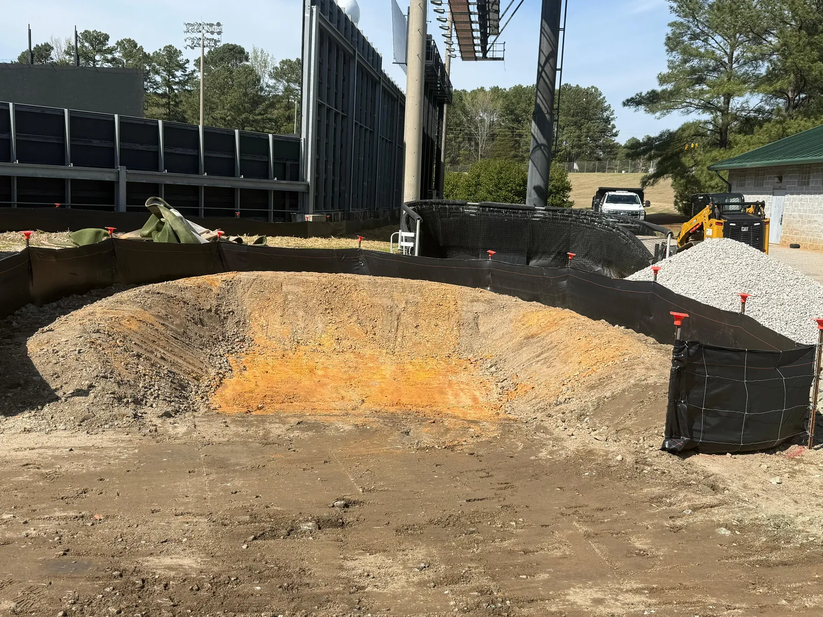 Concrete washout pit under construction with liner and stone base